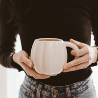 Cream 19 oz pumpkin mug held by a model