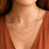 Layered silver ball chain necklace shown on a model