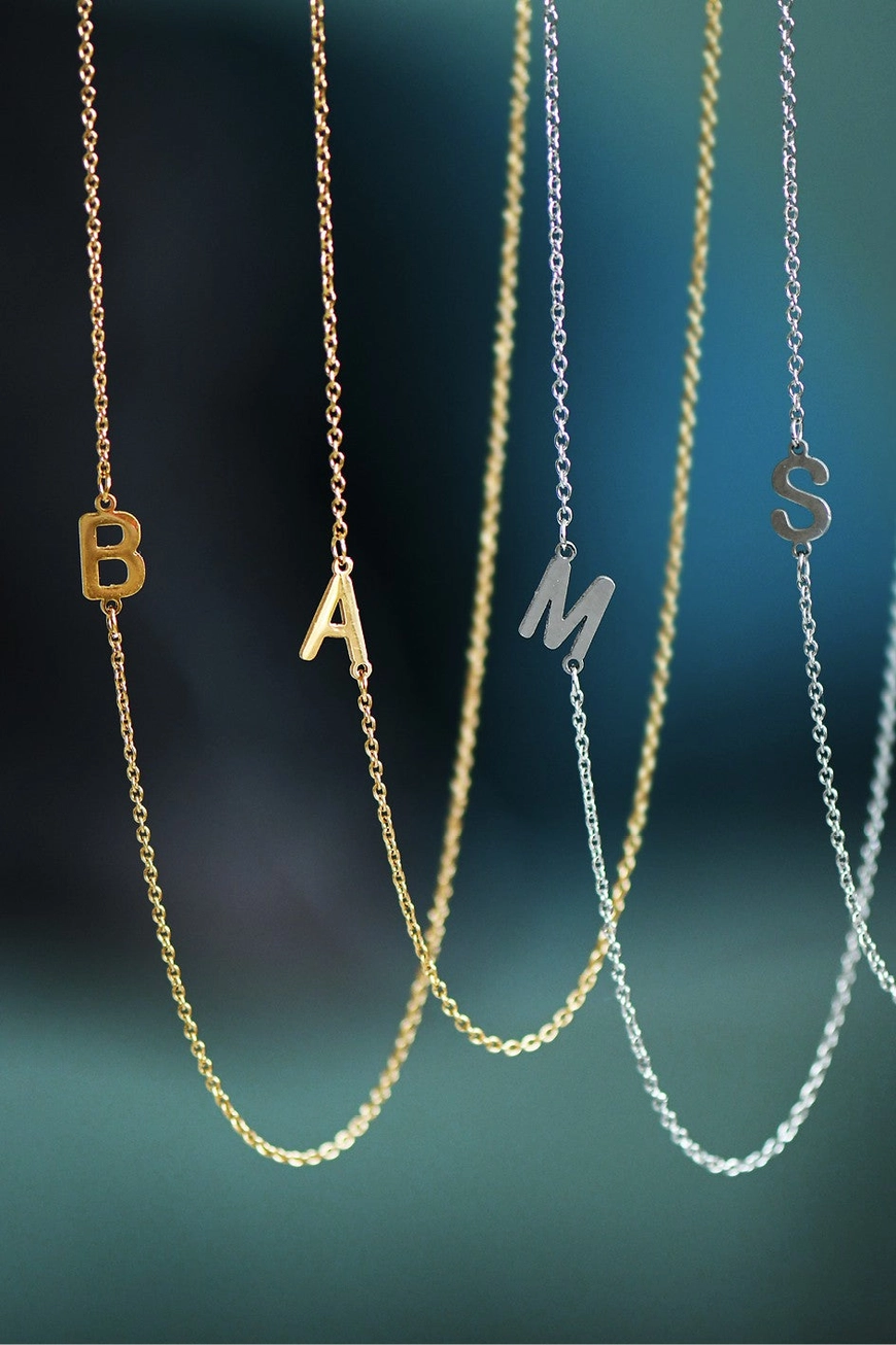 Gold and silver waterproof initial necklaces displayed together