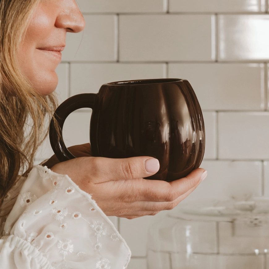 Black 19 oz pumpkin mug held in a kitchen