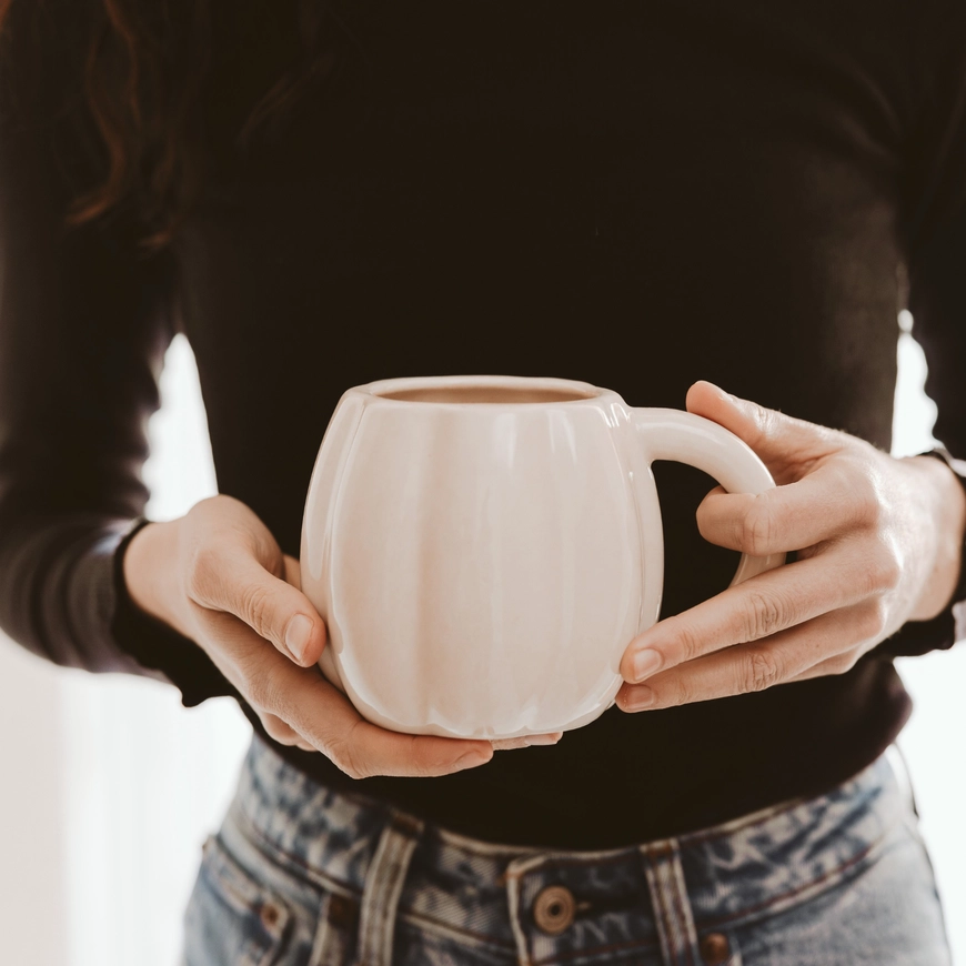 Cream 19 oz pumpkin mug held by a model