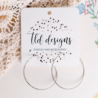 Dainty textured silver-tone hoop earrings on a TLD Designs card