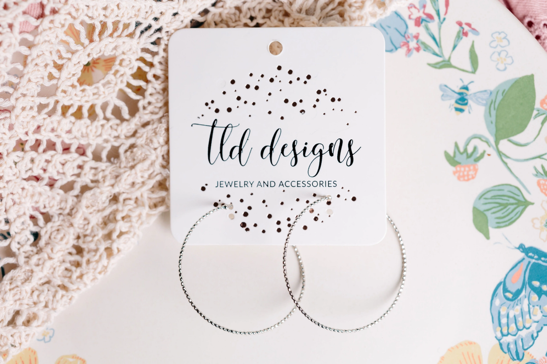 Dainty textured silver-tone hoop earrings on a TLD Designs card