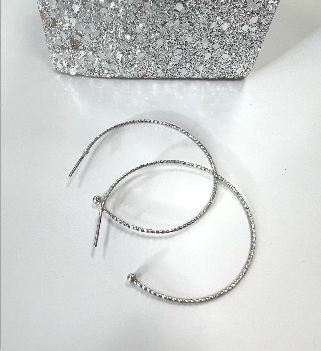 Close-up of slender textured silver-tone hoop earrings