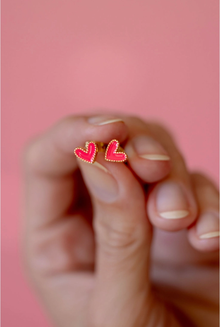 Hot pink enamel heart studs with gold-tone borders held in hand
