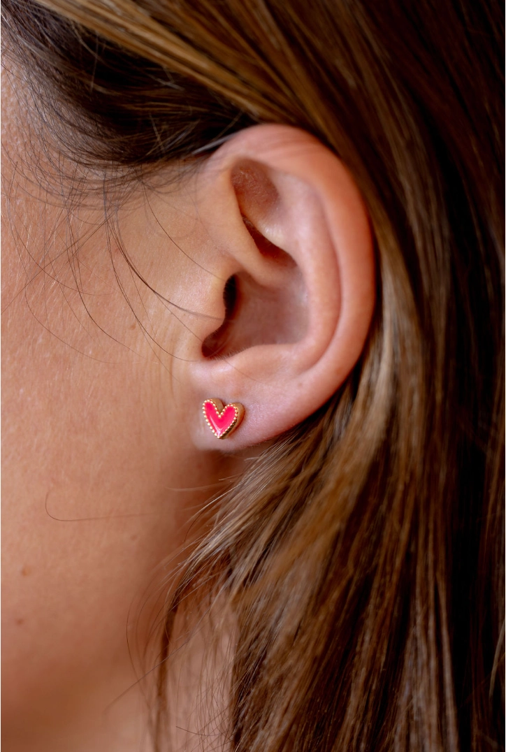 Hot pink enamel heart stud earring worn on an ear
